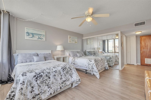 bedroom featuring light hardwood / wood-style floors, ceiling fan, and a textured ceiling