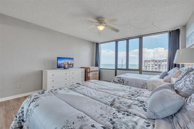 bedroom with ceiling fan, a textured ceiling, light hardwood / wood-style flooring, and expansive windows