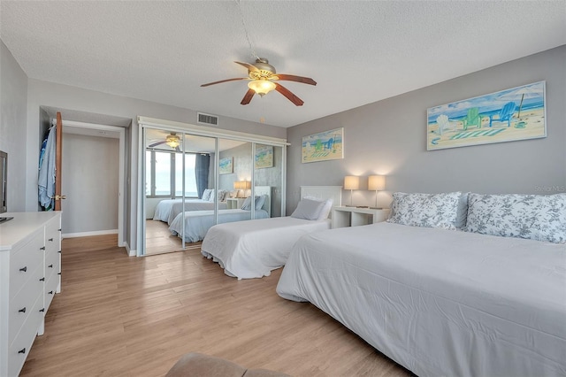 bedroom featuring ceiling fan, a textured ceiling, light hardwood / wood-style flooring, and a closet