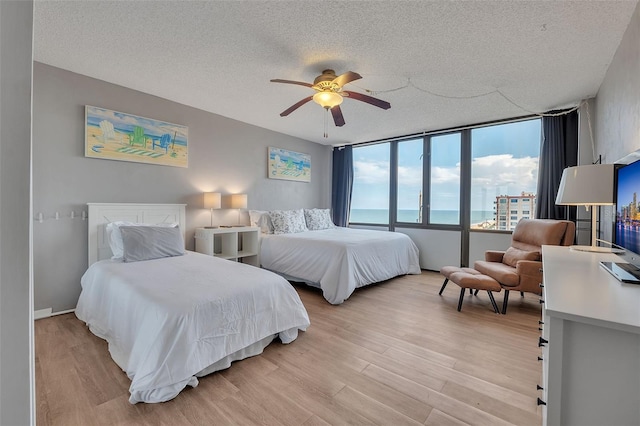 bedroom with ceiling fan, a textured ceiling, and light hardwood / wood-style floors