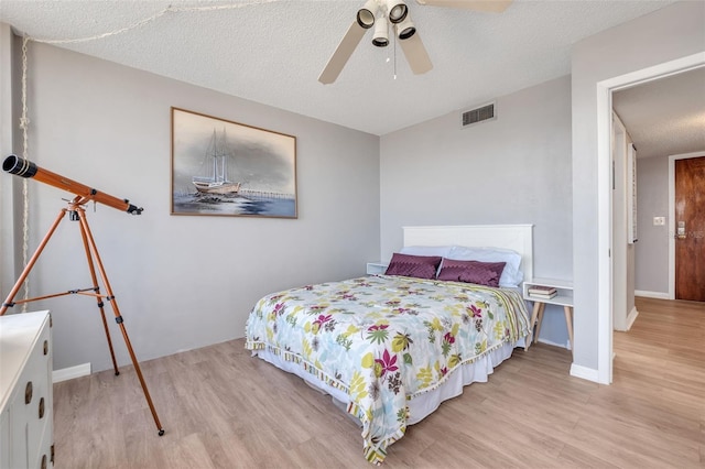 bedroom with light wood-type flooring, ceiling fan, and a textured ceiling