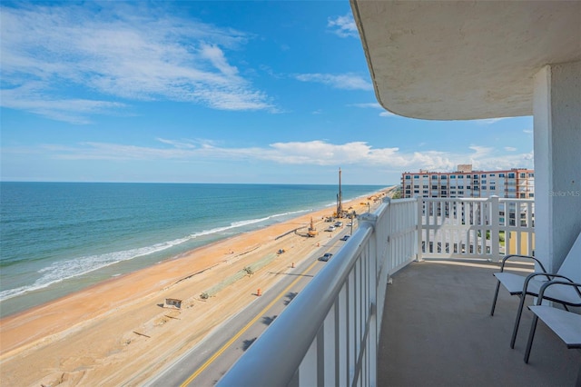 balcony featuring a view of the beach and a water view