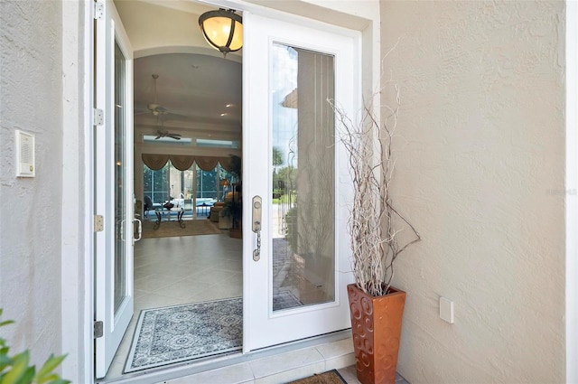 doorway with ceiling fan and light tile patterned floors