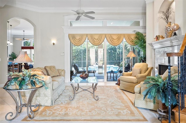 living room with ornamental molding, a fireplace, light tile patterned floors, and ceiling fan