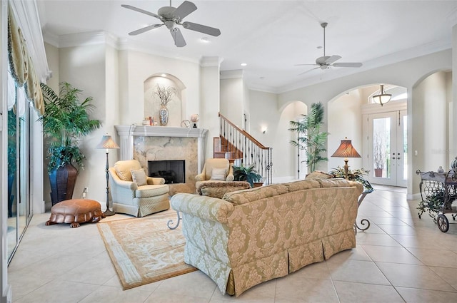 living room featuring crown molding, ceiling fan, and a high end fireplace