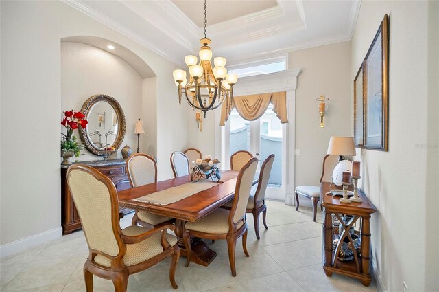 dining space with a tray ceiling, light tile patterned floors, a chandelier, and ornamental molding