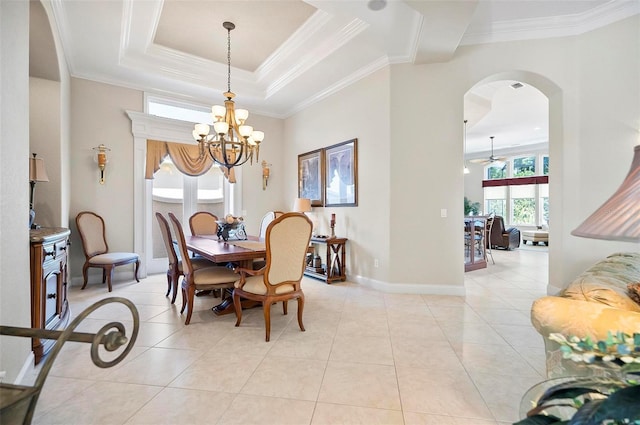 tiled dining space with a tray ceiling, ceiling fan with notable chandelier, and ornamental molding