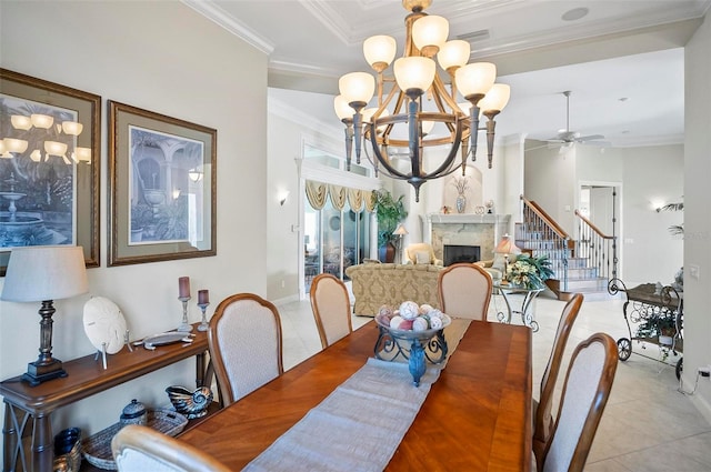 dining room featuring ceiling fan with notable chandelier, a fireplace, ornamental molding, and light tile patterned flooring