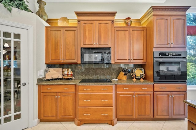 kitchen featuring black appliances, light tile patterned flooring, dark stone counters, and decorative backsplash