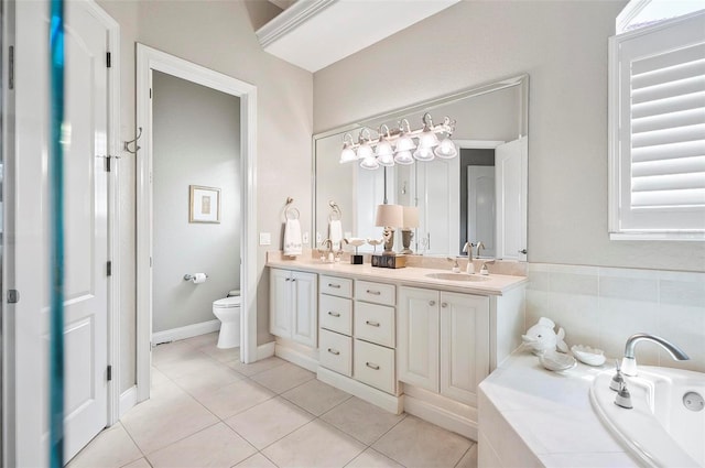 bathroom featuring tile patterned flooring, vanity, toilet, and tiled bath