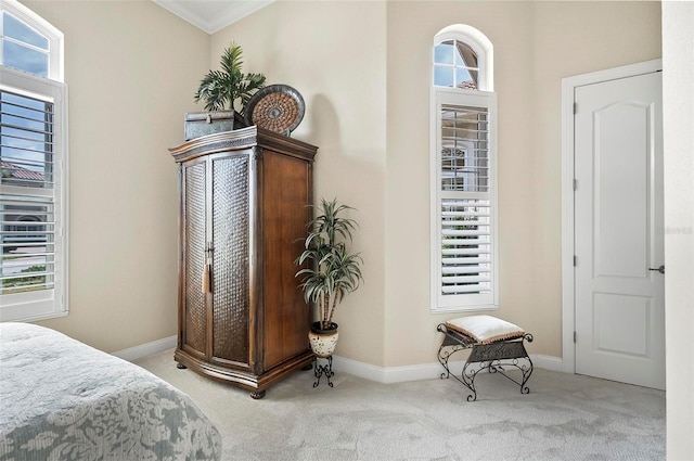 bedroom with ornamental molding and light colored carpet