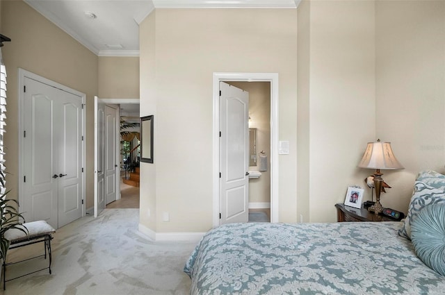 carpeted bedroom with ensuite bathroom and ornamental molding