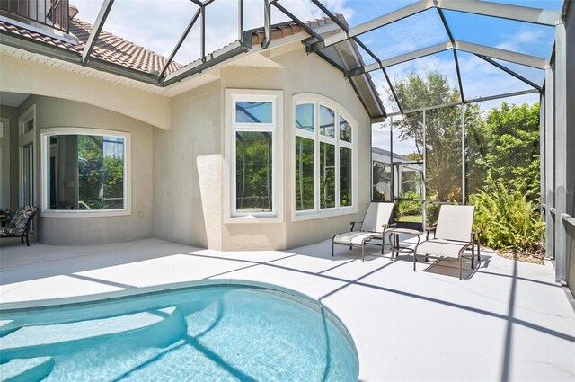 view of pool with glass enclosure and a patio area