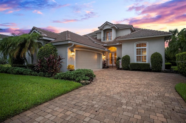 mediterranean / spanish-style house featuring a garage and a lawn