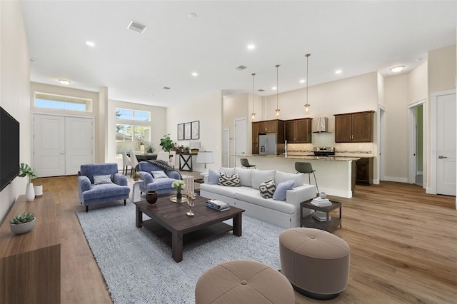 living room featuring recessed lighting, visible vents, baseboards, and light wood-style flooring