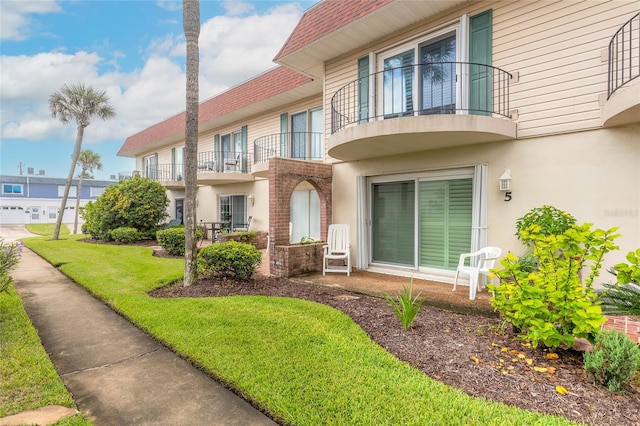 property entrance featuring a lawn and a balcony