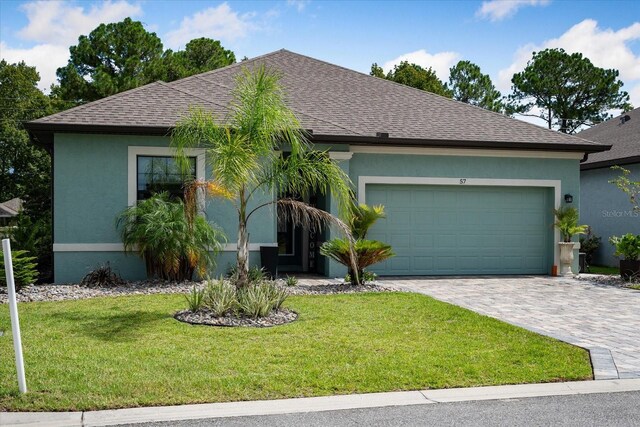 57 Green Cir, Palm Coast, FL 32164 - ranch-style house with roof with shingles, stucco siding, an attached garage, and a front yard