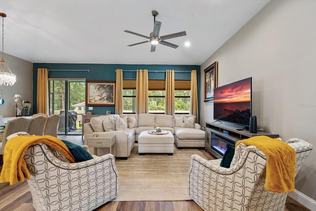 living room featuring ceiling fan with notable chandelier, light wood-type flooring, vaulted ceiling, and a wealth of natural light