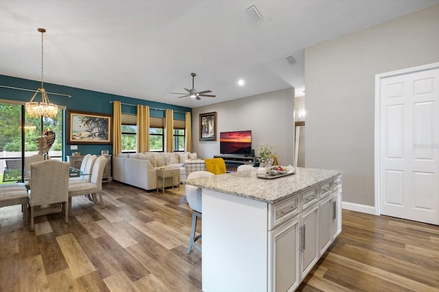 kitchen featuring pendant lighting, light hardwood / wood-style floors, ceiling fan with notable chandelier, white cabinets, and a kitchen island