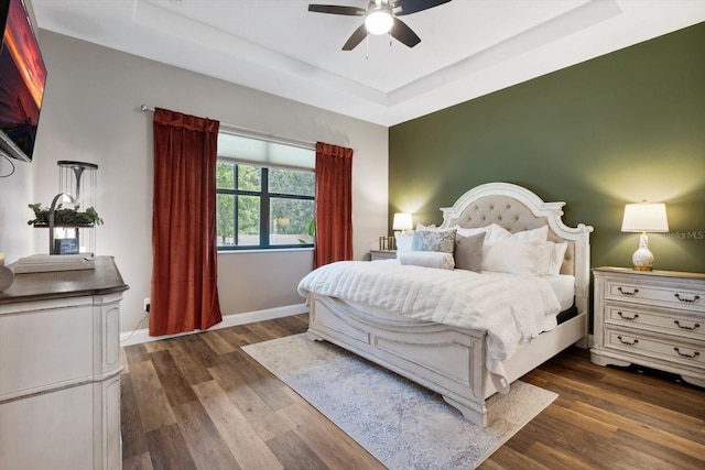 bedroom featuring a tray ceiling, dark hardwood / wood-style floors, and ceiling fan