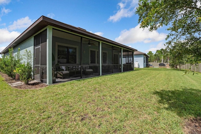 rear view of property with ceiling fan, a sunroom, and a yard