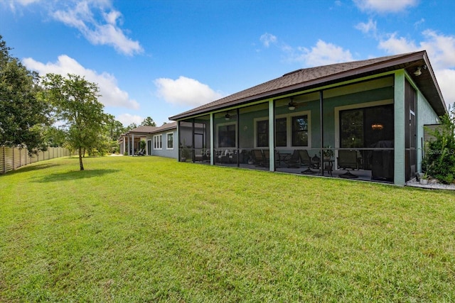 rear view of property featuring a yard, ceiling fan, and a sunroom