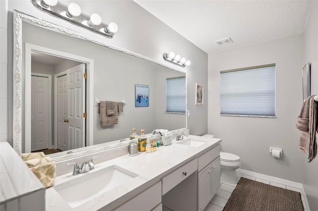 bathroom featuring tile patterned flooring, toilet, a textured ceiling, and vanity