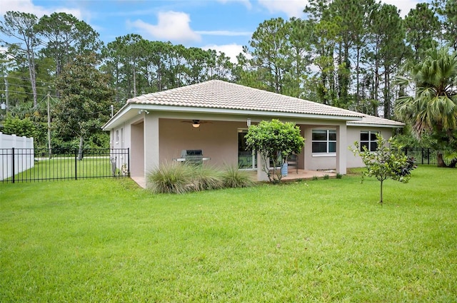 rear view of house featuring ceiling fan, a lawn, and a patio