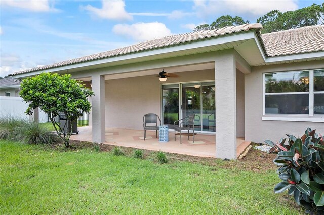 rear view of property with ceiling fan, a yard, and a patio area