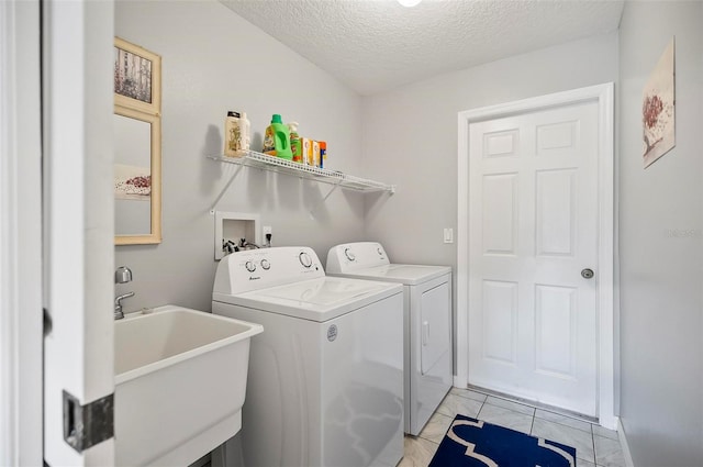 clothes washing area with light tile patterned floors, a textured ceiling, washer and clothes dryer, and sink