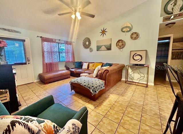 living room featuring lofted ceiling, ceiling fan, and light tile patterned floors