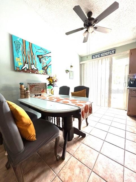 dining room with ceiling fan, light tile patterned floors, and a textured ceiling