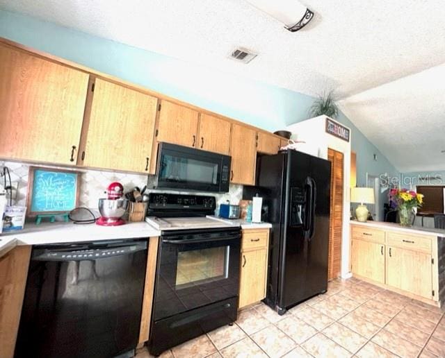 kitchen with lofted ceiling, black appliances, a textured ceiling, and light tile patterned flooring