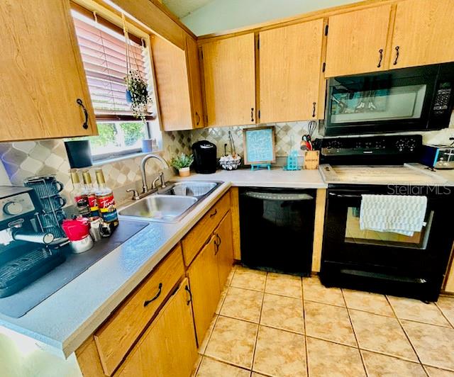 kitchen with decorative backsplash, black appliances, light tile patterned floors, and sink