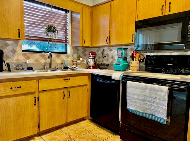 kitchen with black appliances, light tile patterned flooring, backsplash, and sink