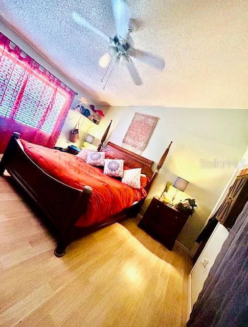 bedroom with ceiling fan, a textured ceiling, and hardwood / wood-style floors