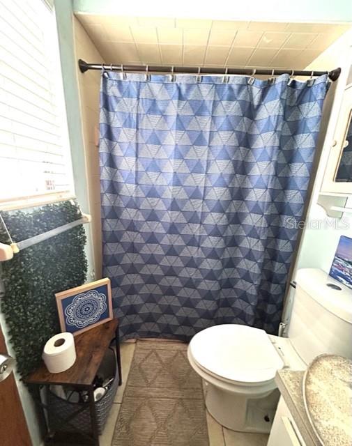 bathroom featuring a shower with shower curtain, vanity, toilet, and tile patterned floors