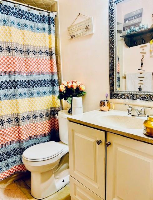 bathroom with vanity, tile patterned floors, toilet, and curtained shower