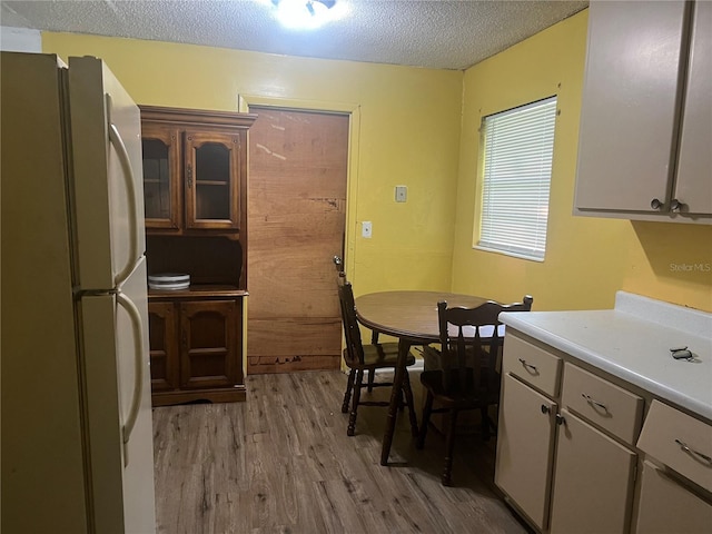 kitchen with a textured ceiling, light hardwood / wood-style floors, white cabinetry, and white refrigerator