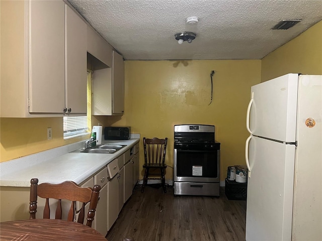 kitchen with sink, a textured ceiling, dark wood-type flooring, stainless steel range oven, and white fridge