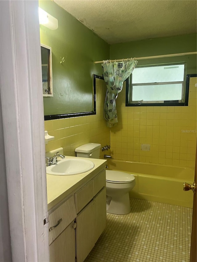 full bathroom with tile walls, shower / bath combo with shower curtain, vanity, tile patterned flooring, and toilet