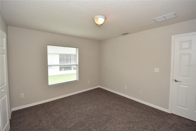 spare room featuring dark carpet and a textured ceiling