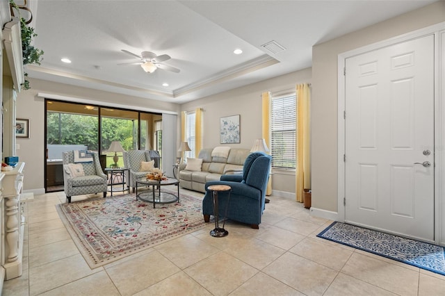 living room featuring ceiling fan, a tray ceiling, ornamental molding, and light tile patterned flooring