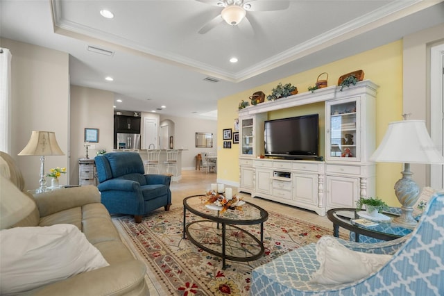 living room with ceiling fan, crown molding, and a tray ceiling