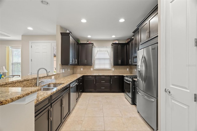 kitchen featuring a healthy amount of sunlight, stainless steel appliances, light stone countertops, and sink