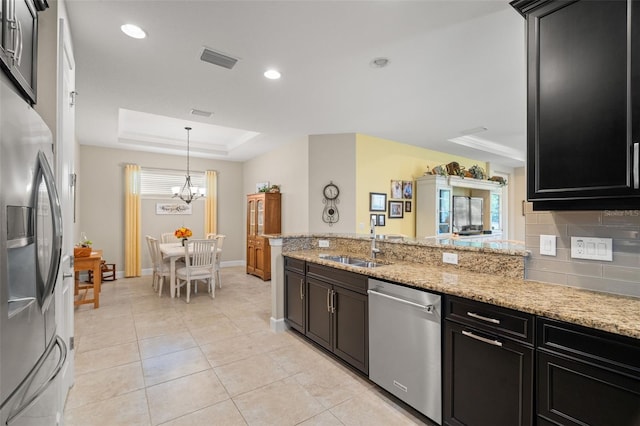 kitchen with light stone counters, appliances with stainless steel finishes, sink, and decorative backsplash