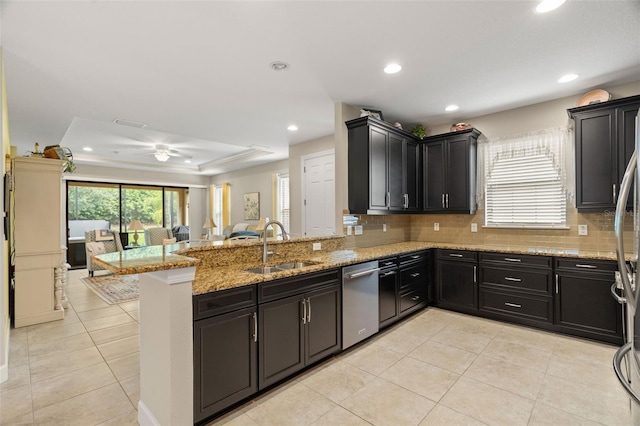 kitchen featuring kitchen peninsula, sink, stainless steel dishwasher, light stone counters, and ceiling fan