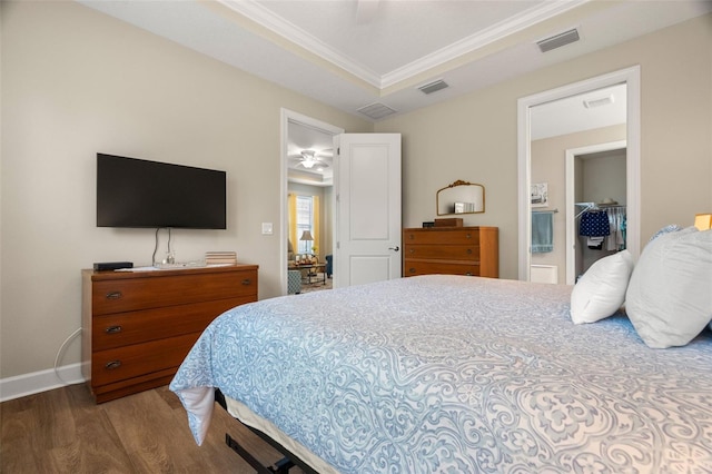 bedroom with ceiling fan, a walk in closet, hardwood / wood-style flooring, crown molding, and a closet