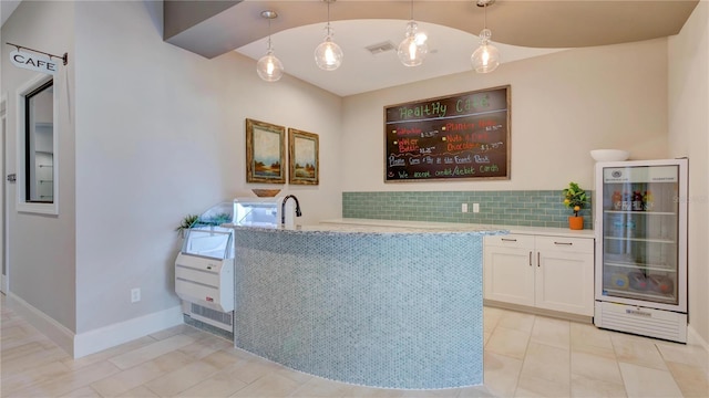 interior space with beverage cooler, light tile patterned flooring, lofted ceiling, pendant lighting, and white cabinets