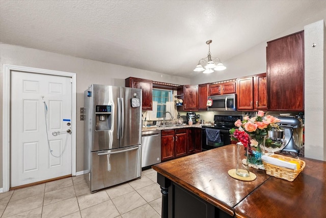 kitchen featuring stainless steel appliances, light tile patterned floors, pendant lighting, sink, and an inviting chandelier